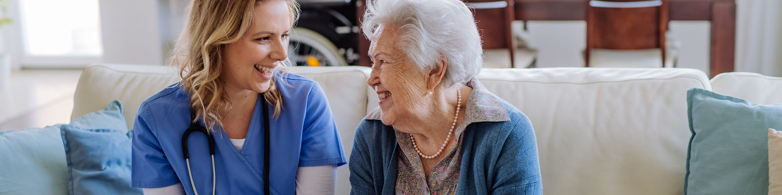 A senior woman sitting with her female nursing assistant on the couch